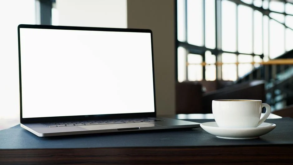 A laptop on a bed showing web design software, creating a cozy workspace.